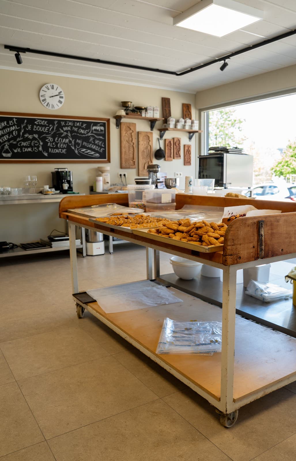 De werktafel in het atelier, met verse koekjes, het schoolbord en de speculaasplanken aan de muur.