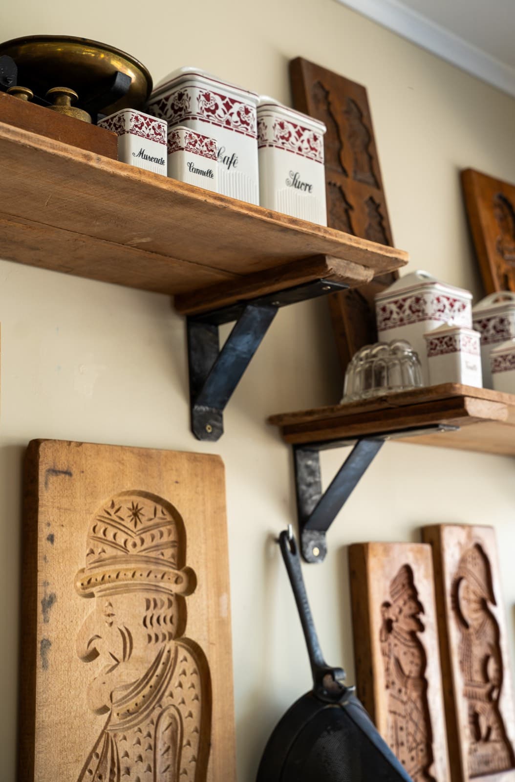 Houten speculaasplanken en voorraadpotten aan de muur van het atelier.